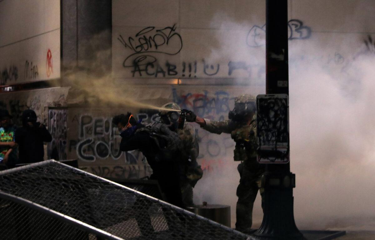 Federal law enforcement officers use pepper spray and tear gas on demonstrators in Portland, Ore., July 19, 2020. (Caitlin Ochs/Reuters)