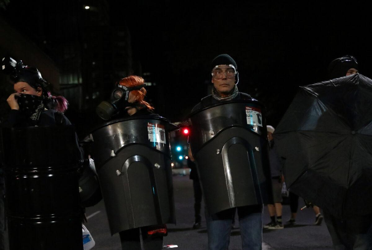 Rioters use garbage cans, umbrellas, and other materials as makeshift shields during clashes with law enforcement in Portland, Ore., on July 19, 2020. (Caitlin Ochs/Reuters)