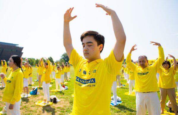 Falun Gong practitioners are practicing exercises on the grass in front of the Washington Monument to urge the stopping of the CCP's persecution of their spiritual discipline, in Washington, D.C. on July 19, 2020. (Lisa Fan/The Epoch Times)