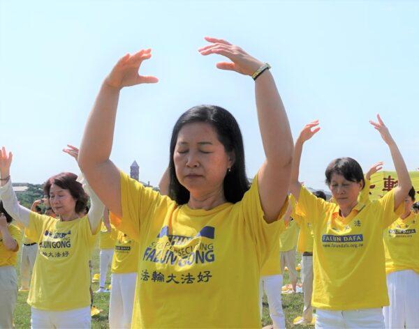 Falun Gong practitioners are practicing exercises on the grass in front of the Washington Monument to urge the stopping of the CCP's persecution of their spiritual discipline, in Washington, D.C. on July 19, 2020. (Yi Ping/The Epoch Times)