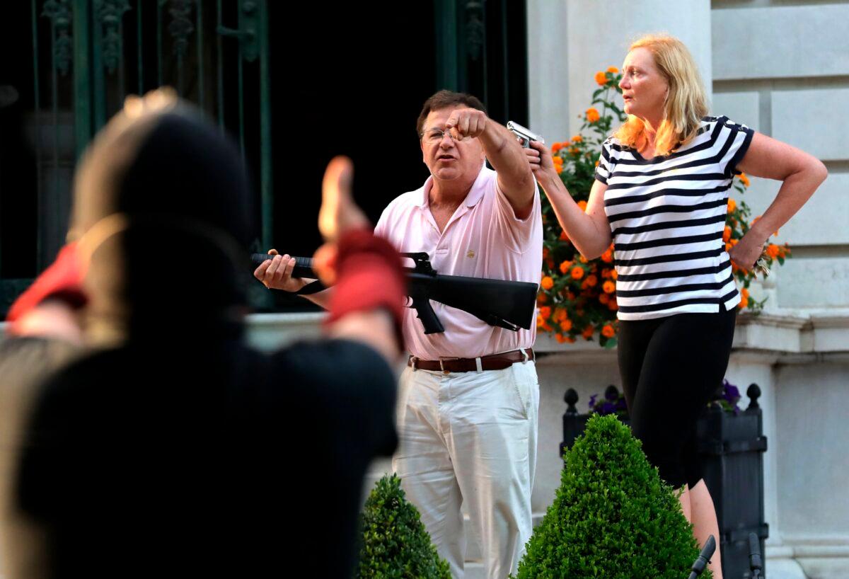 Armed homeowners Mark and Patricia McCloskey stand in front of their house along Portland Place to confront protesters in the Central West End of St. Louis, on June 28, 2020. (Laurie Skrivan/St. Louis Post-Dispatch via AP)