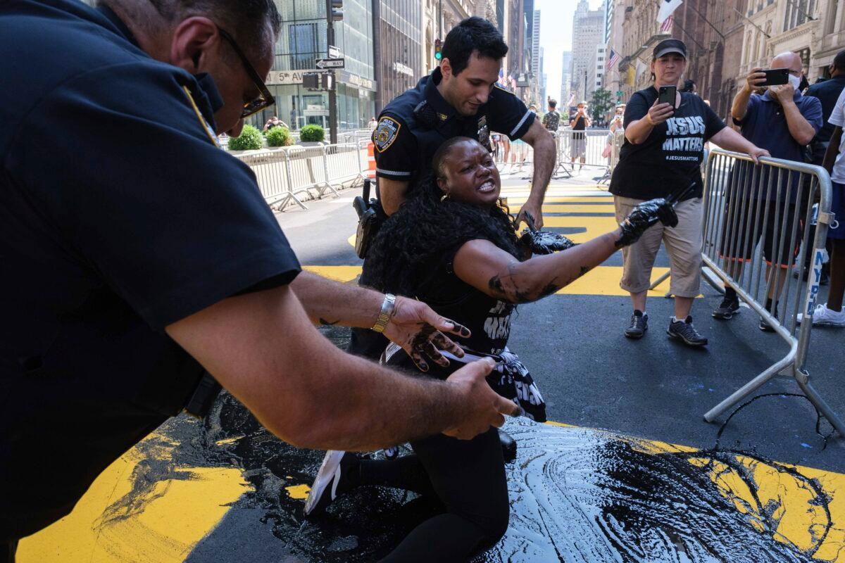 NYPD officers attempt to detain Bevelyn Beatty, who poured black paint on the Black Lives Matter mural outside of Trump Tower on 5th Avenue in the Manhattan borough of New York, on July 18, 2020. (Yuki Iwamura/AP Photo)