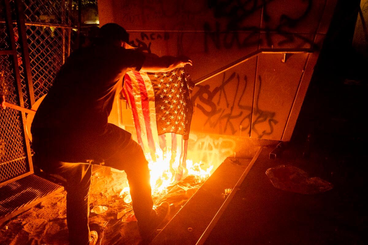 A Black Lives Matter protester burns an American flag outside the Mark O. Hatfield United States Courthouse on July 20, 2020, in Portland, Ore. Several hundred demonstrators gathered at the courthouse where federal officers deployed teargas and other crowd control munitions. (AP Photo/Noah Berger)