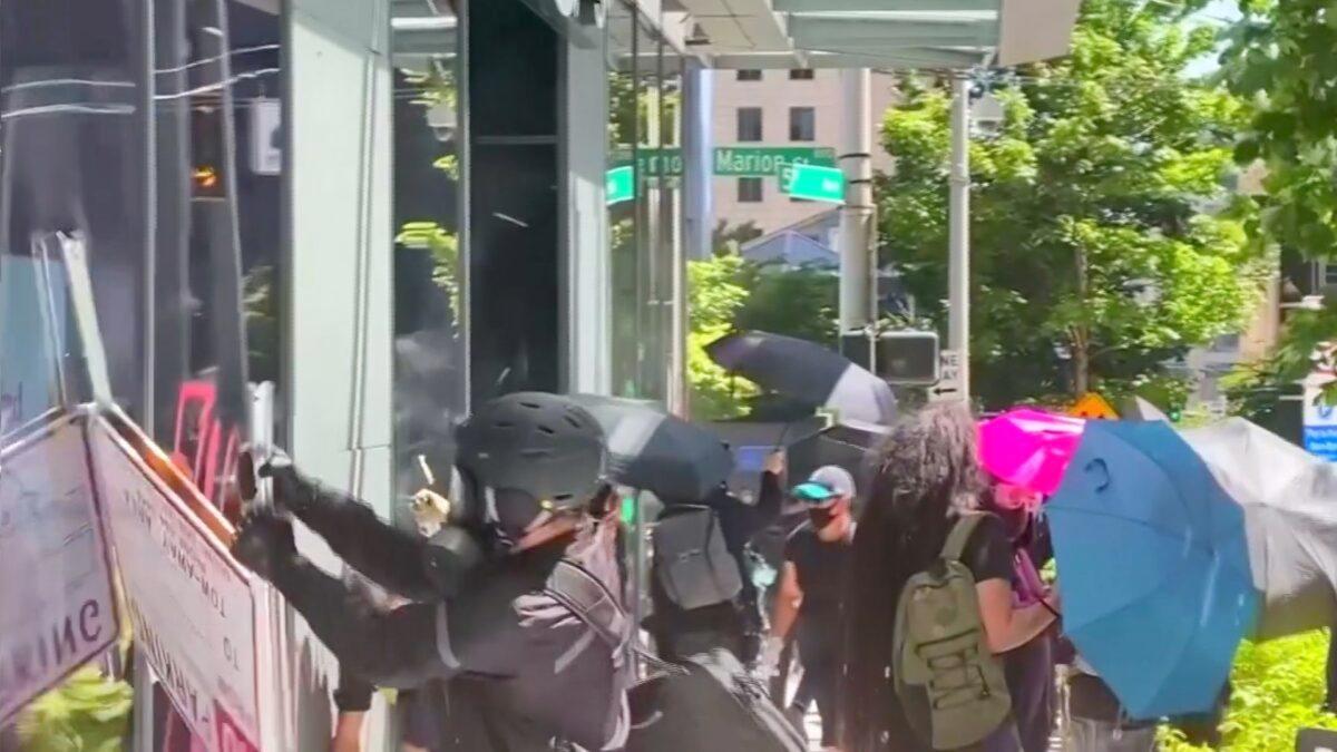 In this still file photograph taken from video, rioters try to break into an Amazon store in Seattle on July 19, 2020. (Katie Daviscourt via Reuters)