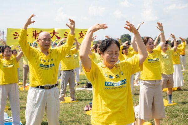 Falun Gong practitioners are practicing exercises on the grass in front of the Washington Monument to urge the stopping of the CCP's persecution of their spiritual discipline, in Washington, D.C. on July 19, 2020. (Lynn Lin/The Epoch Times)
