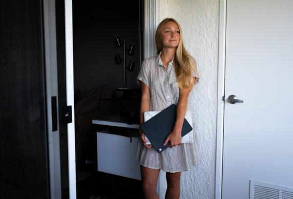 Kelly Mundell, who started her own marketing business just prior to the COVID-19 pandemic, stands with her laptop on a porch in Dana Point, Calif., on July 9, 2020. (John Fredricks/The Epoch Times)