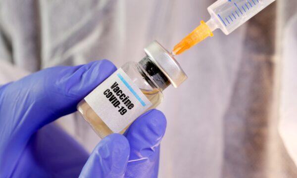 A woman holds a small bottle labeled with a "Vaccine COVID-19" sticker and a medical syringe in this illustration taken on April 10, 2020. (Dado Ruvic/Illustration/Reuters)