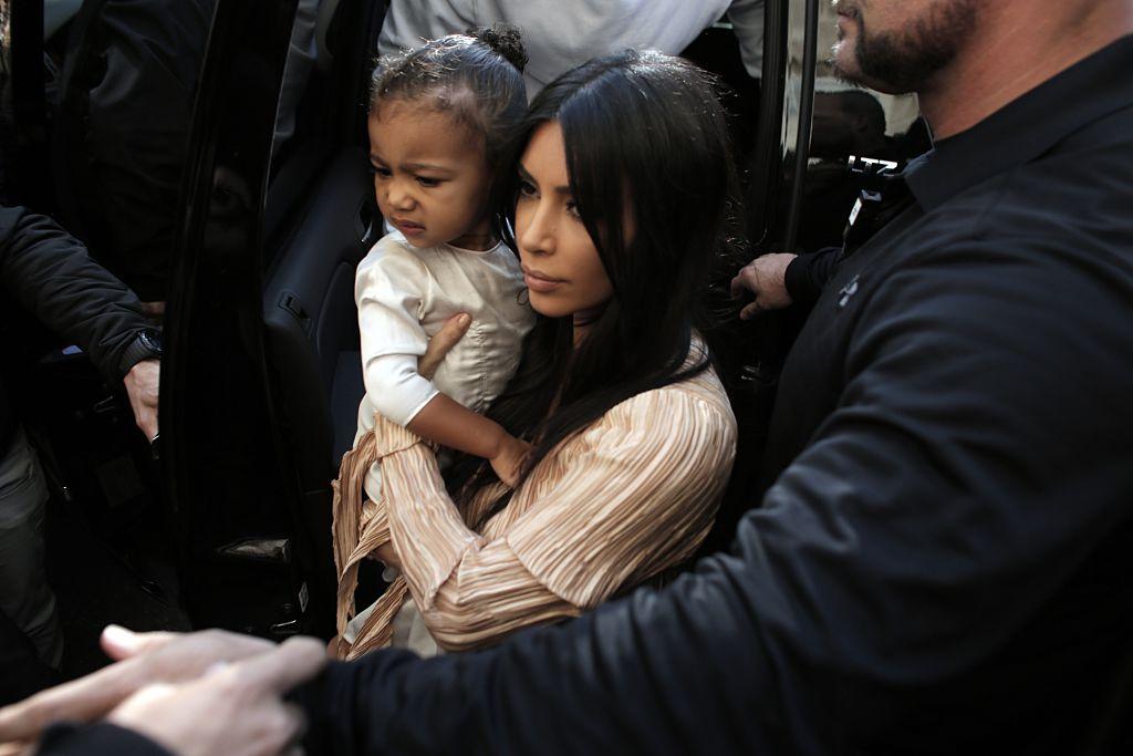 Kim carries her daughter, North West, as she and Kanye arrive at the Armenian St. James Cathedral in Jerusalem's Old City on April 13, 2015. (AHMAD GHARABLI/AFP via Getty Images)