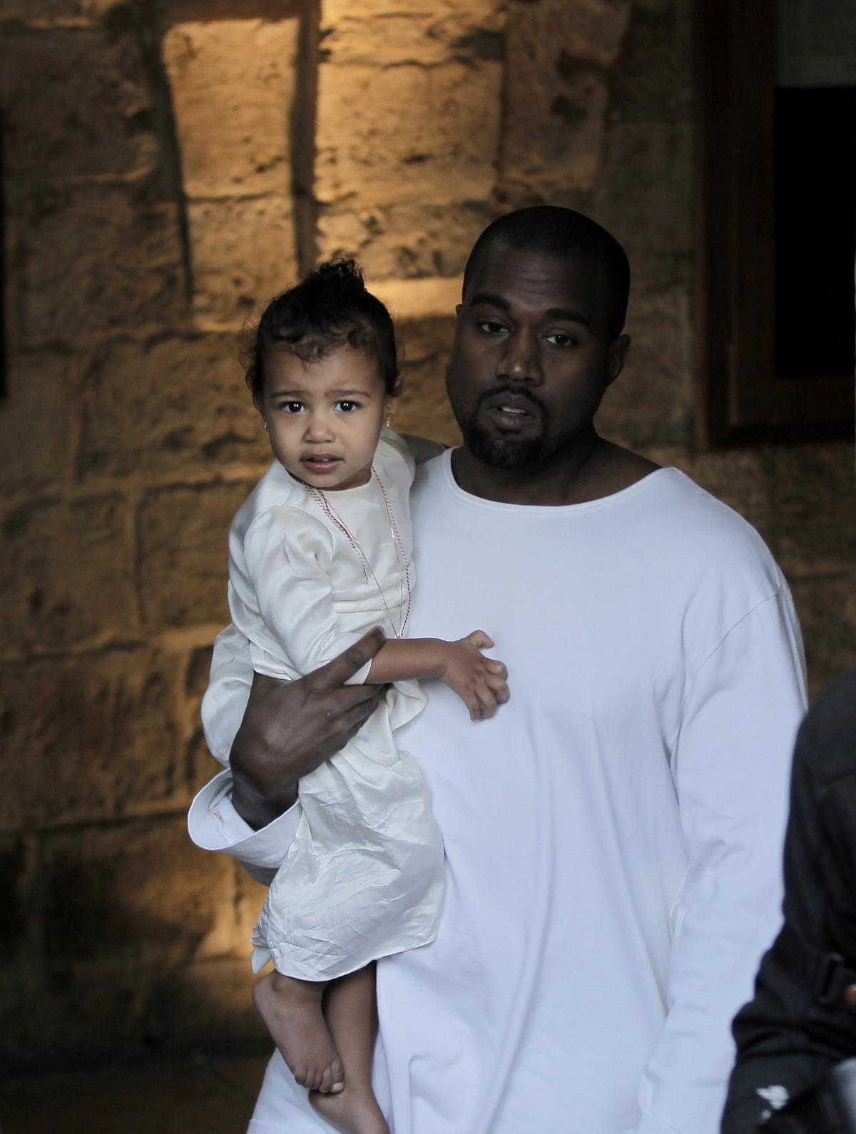Kanye West carries his daughter, North, following a reported baptism ceremony at the Armenian St. James Cathedral in Jerusalem's Old City on April 13, 2015. (AHMAD GHARABLI/AFP via Getty Images)