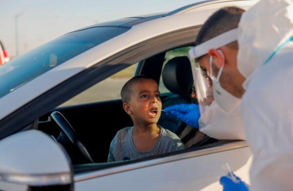 A paramedic with Israel's Magen David Adom (Red Shield of David) national emergency medical service, swabs a boy for COVID-19, at a drive-thru testing site in the Israeli city of Lod on July 15, 2020. (Ahmad Gharabli / AFP via Getty Images)