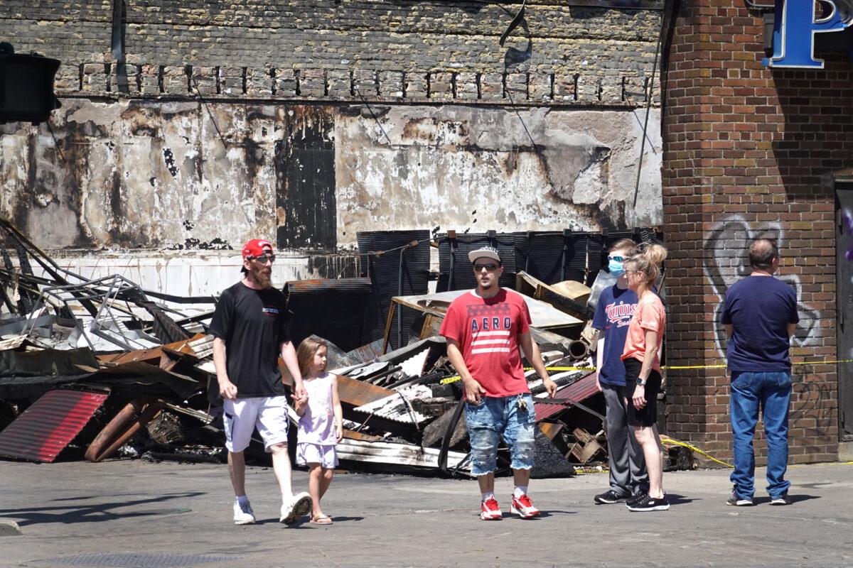 People walk past the charred remains of a pawn shop destroyed during last week's rioting, in Minneapolis, Minn., on June 3, 2020. (Scott Olson/Getty Images)