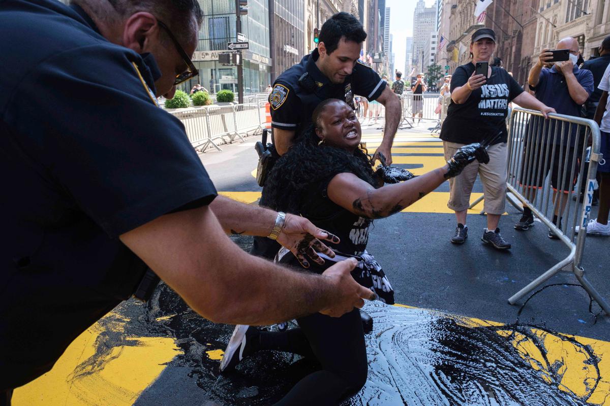 NYPD officers attempt to detain Bevelyn Beatty, 29, who poured black paint on the Black Lives Matter mural outside Trump Tower on Fifth Avenue in Manhattan on Saturday, July 18, 2020. (Yuki Iwamura/AP Photo)