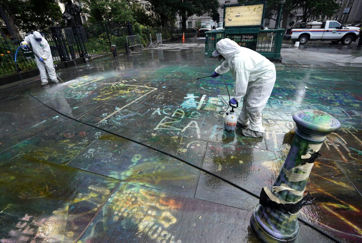 Sanitation workers use a pressure washer to remove graffiti near City Hall in New York City on July 22, 2020. (Timothy A. Clary/AFP via Getty Images)