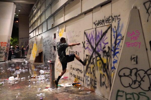 A protester kicks an entrance to the Mark O. Hatfield Courthouse after federal officers took shelter inside, in Portland, Ore., on July 21, 2020. (Nathan Howard/Getty Images)