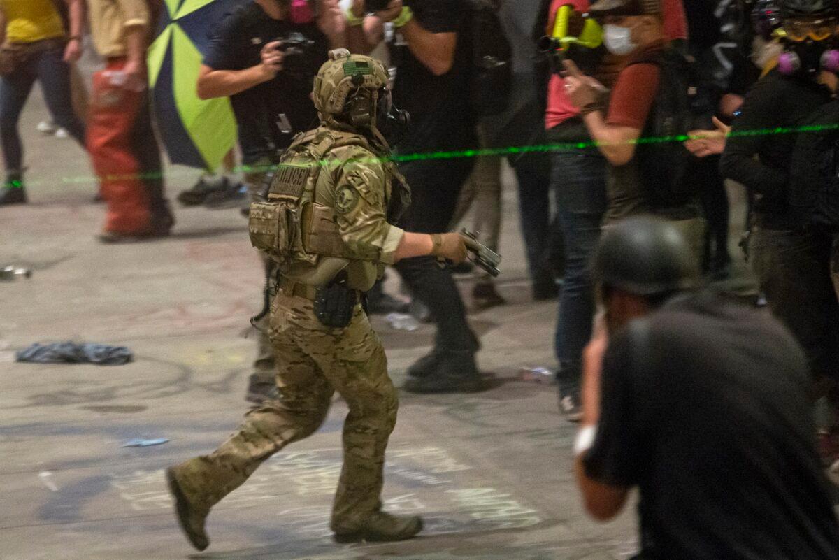 A federal officer pulls his sidearm while dispersing a crowd of about a thousand at the Mark O. Hatfield U.S. Courthouse in Portland, Ore., on July 20, 2020. (Nathan Howard/Getty Images)