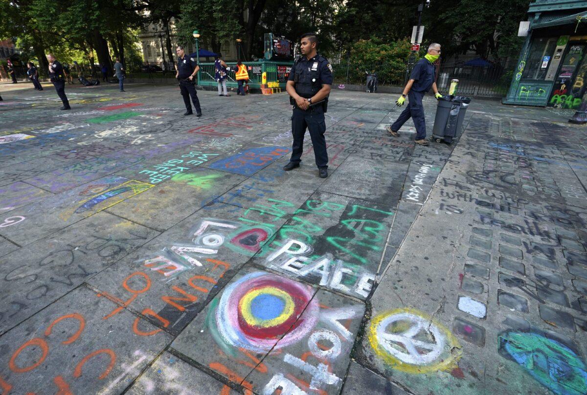 New York police officers standby as sanitation workers remove graffiti at the site of Occupy City Hall protest in New York City on July 22, 2020. (Timothy A. Clary/AFP via Getty Images)