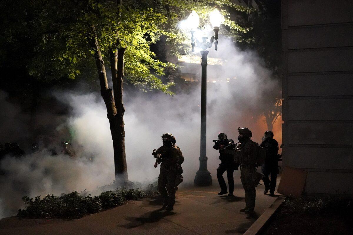 Federal officers walk through tear gas while dispersing a crowd of about a thousand people during a protest at the Mark O. Hatfield U.S. Courthouse in Portland, Ore., on July 21, 2020. (Nathan Howard/Getty Images)