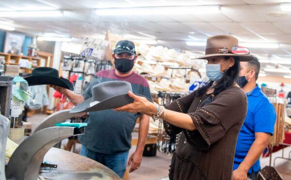 A woman shapes a Stetson hat in front of clients while wearing a mask at the manufacture store in Garland, Texas on July 20, 2020.. (Valerie Macon/AFP via Getty Images)