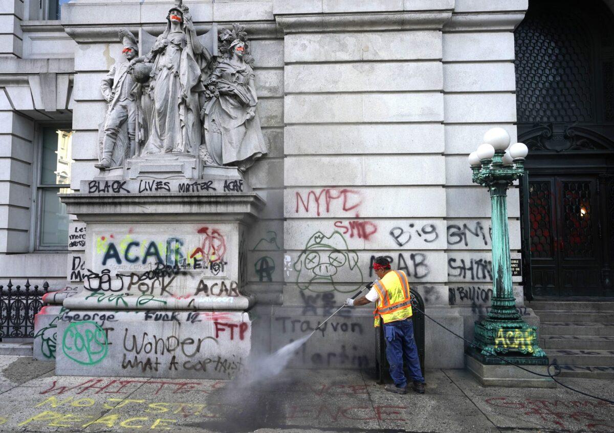 Sanitation workers clean up graffiti at the site of Occupy City Hall protest in New York City on July 22, 2020. (Timothy A. Clary/AFP via Getty Images)