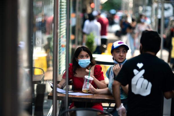 Customers wear protective masks as they order food outside a restaurant in New York City, on July 21, 2020. (Jeenah Moon/Getty Images)