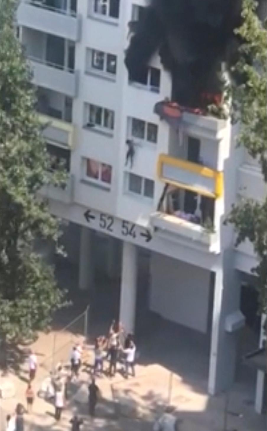 In this grab taken from video, a boy jumps from a window as flames engulf an apartment as onlookers below prepare to catch him in Grenoble, France, Tuesday, July 21, 2020. (AP)