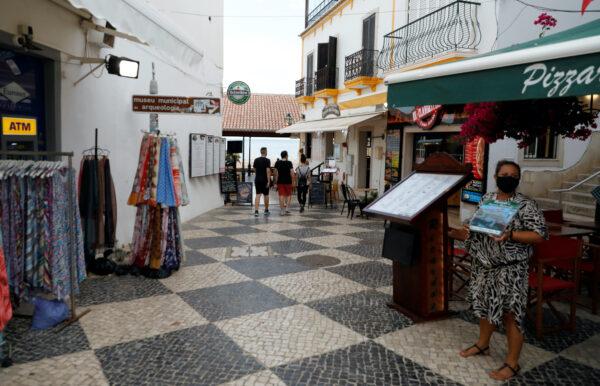 A server offers the menu on a street during the coronavirus disease (COVID-19) pandemic in downtown Albufeira, Portugal, on July 20, 2020. (Rafael Marchante/Reuters）
