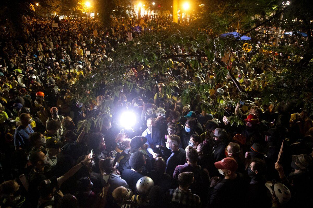 Portland Mayor Ted Wheeler wades through the large crowd, where his stated goal was to conduct a "listening session," during a night of protest in Portland on July 22, 2020. (Beth Nakamura/The Oregonian via AP)