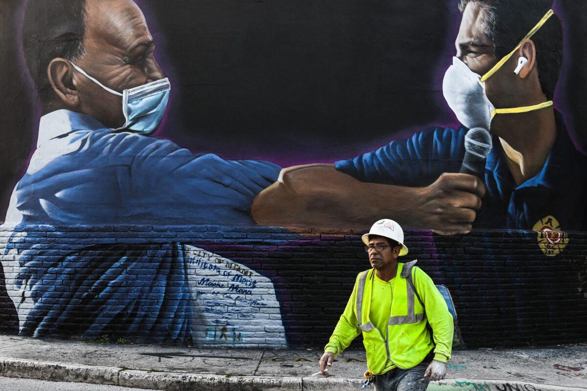  A construction worker walks past a mural of Moishe Mana, left, and Miami Mayor Francis Suarez wearing masks in Wynwood Art District in Miami, Fla., on June 29, 2020. (Chandan Khanna/AFP via Getty Images)