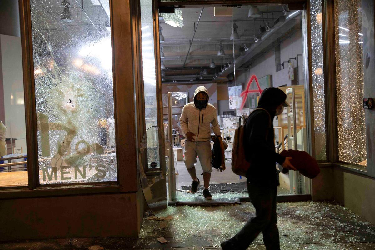 Looters emerge from an Urban Outfitters store with merchandise during a riot on May 30, 2020 in Seattle, Washington. (Karen Ducey/Getty Images)