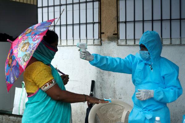 A healthcare worker checks the temperature and pulse of a resident during a check-up camp for the coronavirus disease (COVID-19), in Mumbai, India, July 4, 2020. (Francis Mascarenhas/Reuters)