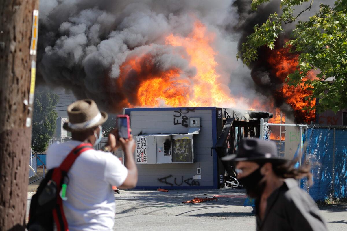 Construction buildings burn near the King County Juvenile Detention Center, Sat., July 25, 2020, in Seattle, shortly after protesters left the area. A large group of protesters were marching Saturday in Seattle in support of Black Lives Matter and against police brutality and racial injustice. Protesters broke windows and vandalized cars at the facility. (Ted S. Warren/AP Photo)