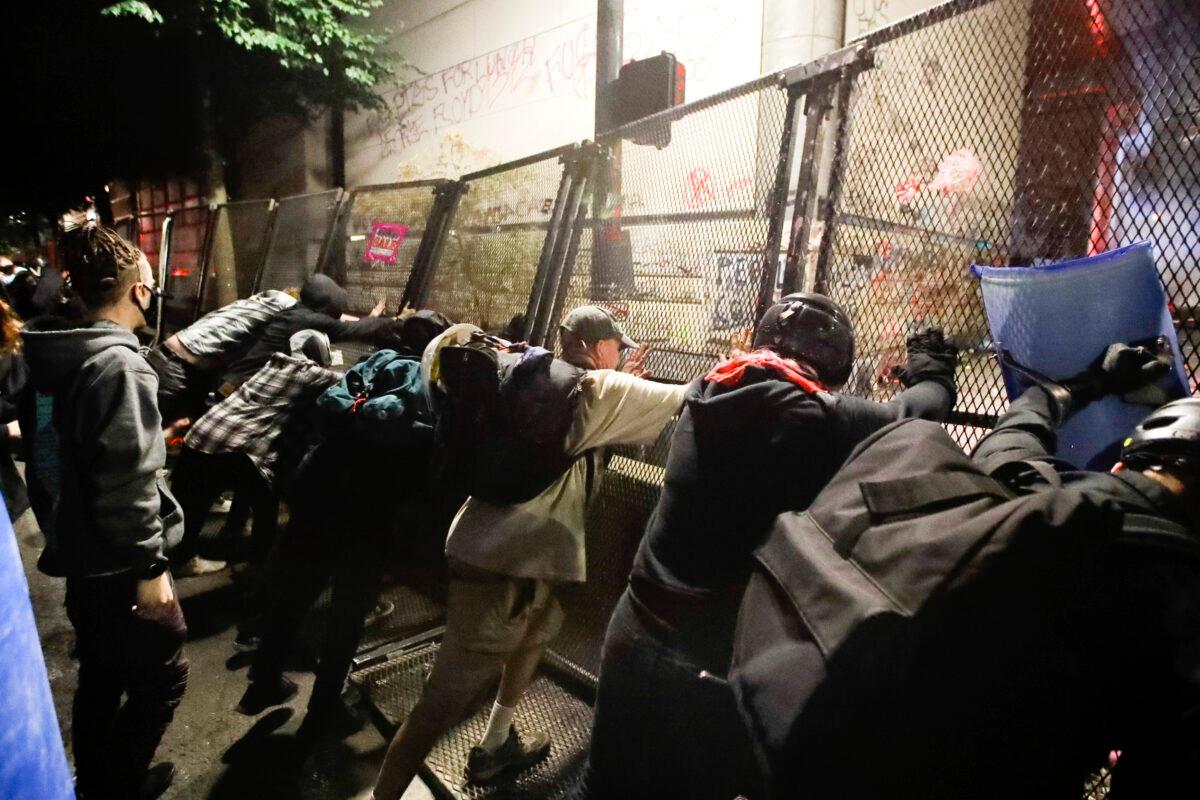 Demonstrators try to topple a steel fence during a Black Lives Matter protest at the Mark O. Hatfield courthouse in Portland, Ore., on July 25, 2020, (Marcio Jose Sanchez/AP Photo)