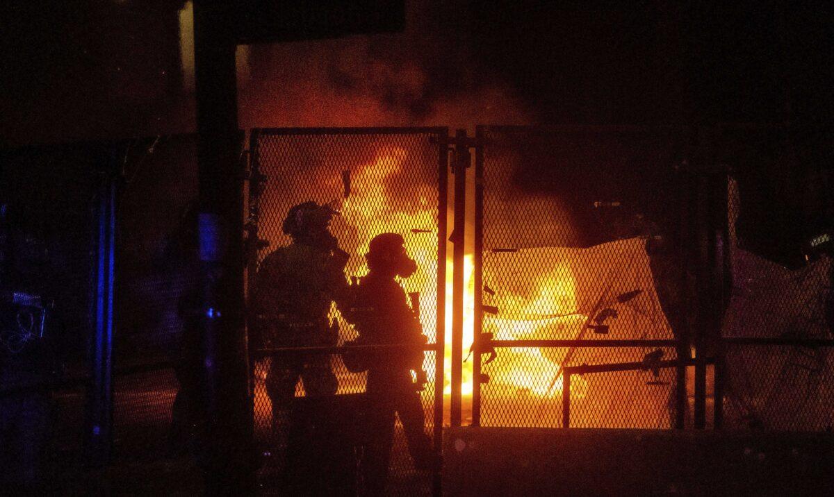 Federal officers guard the Mark O. Hatfield U.S. Courthouse as a fire lit by rioters burns on the other side of a perimeter fence, in Portland, Ore., on July 25, 2020. (Noah Berger/AP Photo)