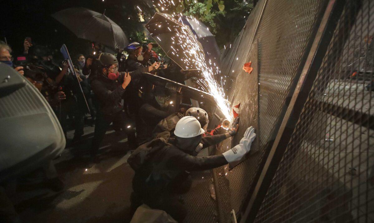 Rioters cut through a steel fence at the Mark O. Hatfield U.S. Courthouse in Portland, Ore., on July 24, 2020. (Marcio Jose Sanchez/AP Photo)