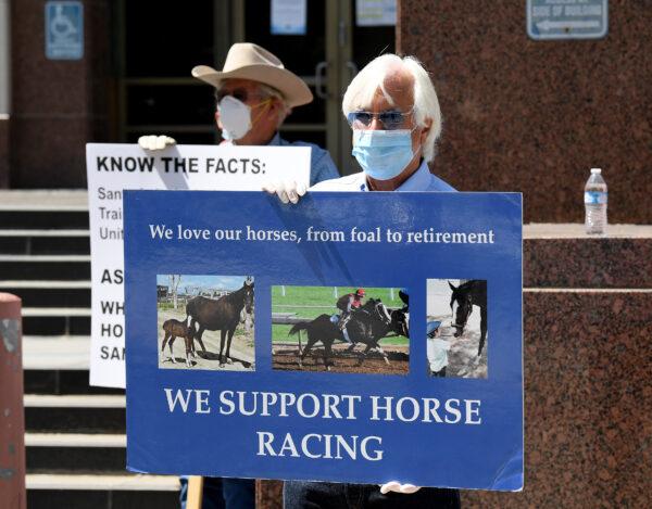  Trainer Bob Baffert holds a sign as he joins horse racing industry workers in the call to reopen Santa Anita Park in front of the offices of the Board of Supervisors of Los Angeles on April 28, 2020. (Harry How/Getty Images)