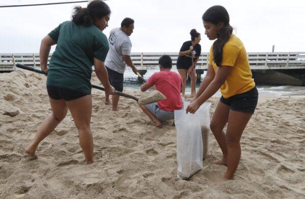 The Keo family assisted the Aubrey family with sandbagging for the preparation of Hurricane Douglas in Hauula, Hawaii on July 26, 2020. Pictured from left-right are, is Keonaona Keo, 17, Aaron Keo, Malu Keo, Amy Aubrey, and Hiwa Keo, 12. (Cindy Ellen Russell/Honolulu Star-Advertiser via AP)