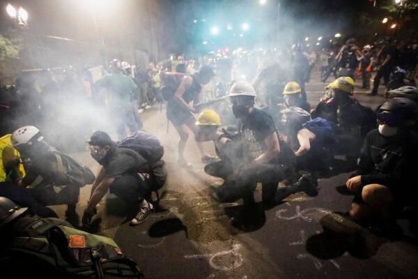 Demonstrators sit and kneel as tear gas fills the air during a Black Lives Matter protest at the Mark O. Hatfield United States Courthouse in Portland, Ore., on July 26, 2020. (Marcio Jose Sanchez/AP Photo)