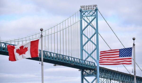 Canadian and American flags fly near the Ambassador Bridge at the Canada-USA border crossing in Windsor, Ont., on March 21, 2020. (Rob Gurdebeke/The Canadian Press)