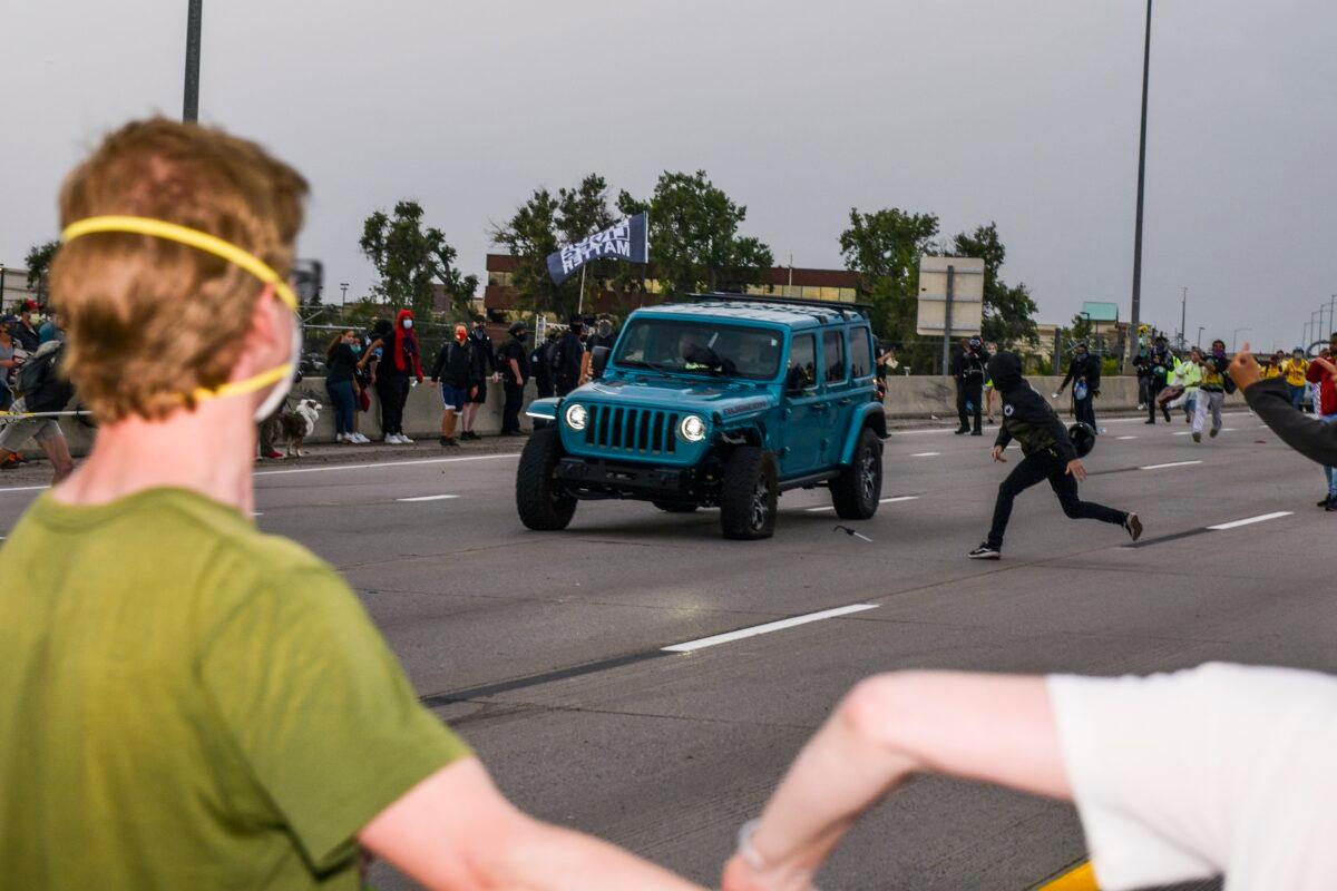 A protester hurls an object at a Jeep as the driver passes by a protest after protesters scattered, in Aurora, Colo., on July 25, 2020. (Michael Ciaglo/Getty Images)