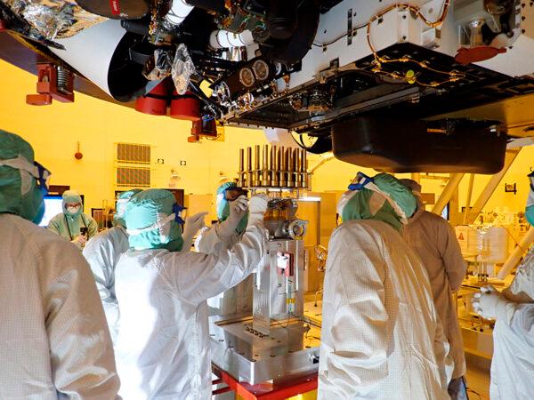 Engineers and technicians insert sample tubes into the belly of the Perseverance Mars rover at the Kennedy Space Center, Fla., on May 20, 2020. (NASA/JPL-Caltech via AP)
