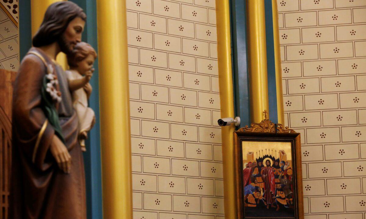 A surveillance camera is seen near a religious painting during a mass at Xishiku Cathedral, a government-sanctioned Catholic church, on Christmas Eve in Beijing, China, on Dec. 2019. (Florence Lo/Reuters)