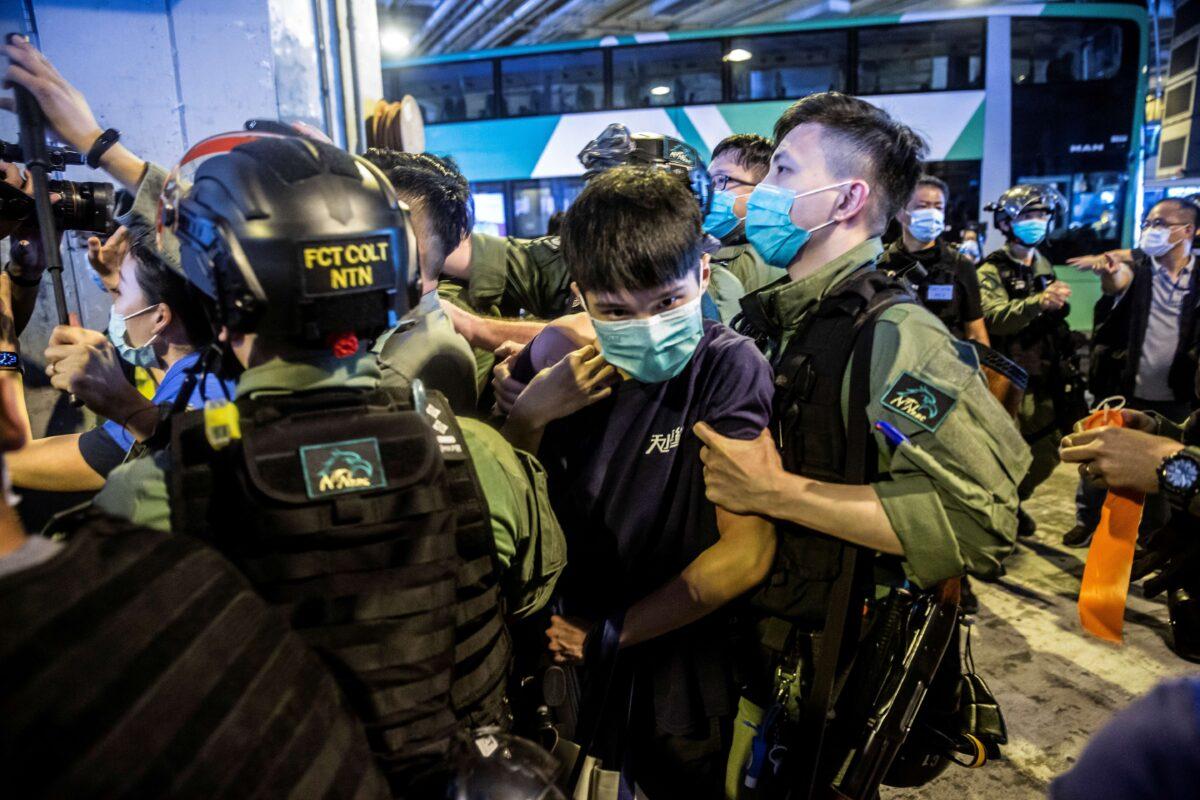A riot police officer (R) detains a man (C) during a protest by district councillors at a mall in Yuen Long in Hong Kong on July 19, 2020. (Isaac Lawrence/AFP via Getty Images)