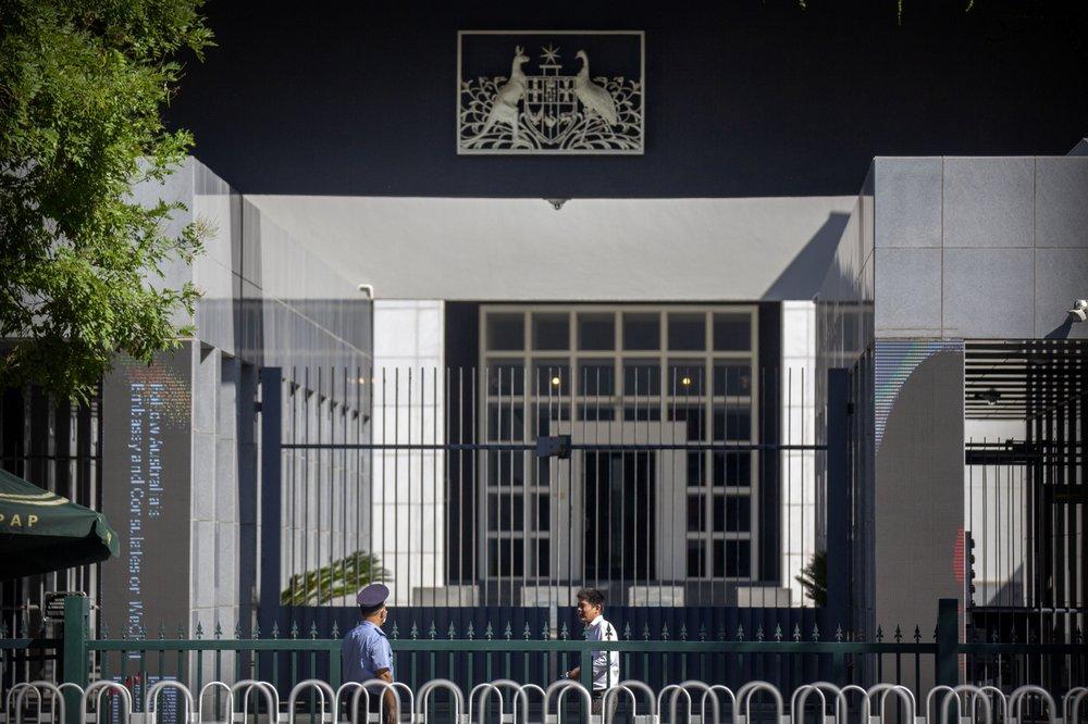 People stand at the gates of the Australian Embassy in Beijing, on Sept. 1, 2020. (AP Photo/Mark Schiefelbein)