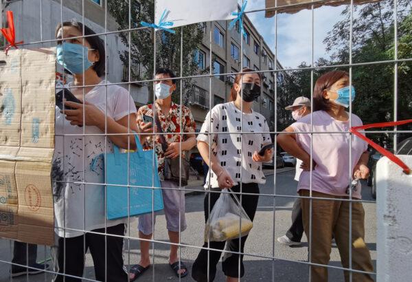 Residents wait for groceries delivered to an entrance of a sealed residential compound, after new cases of coronavirus disease (COVID-19) were confirmed in Dalian, Liaoning province, China, on July 23, 2020. (China Daily via REUTERS)