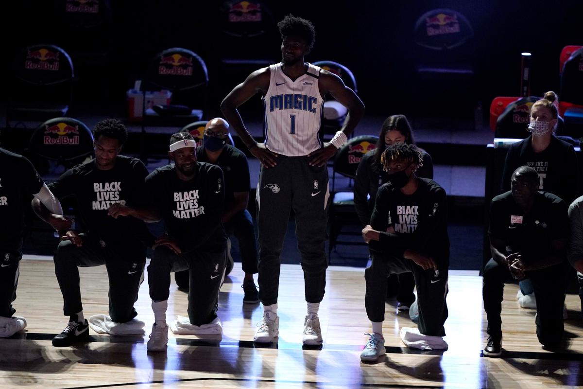 Orlando Magic's Jonathan Isaac stands as others kneel before the start of an NBA basketball game between the Brooklyn Nets and the Orlando Magic Friday, July 31, 2020, in Lake Buena Vista, Fla. (Ashley Landis, Pool/AP Photo)