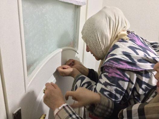 Gulbakhar Jalilova demonstrating the "hole in the door" where her head was shaved, in Istanbul in October, 2019. (Ethan Gutmann)