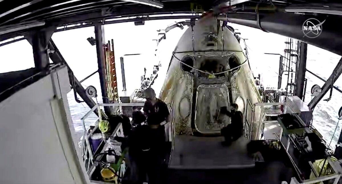 Engineers do a purge of vapor fumes around the Dragon Endeavour with NASA astronauts Robert Behnken and Douglas Hurley aboard after the capsule splashed down in the Gulf of Mexico, on Aug. 2, 2020, in this still image taken from a video. (NASA/Handout via Reuters)