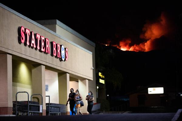 Fire blazes in the background near Stater Bros., where many Black Lives Matter protesters parked their vehicles ahead of a demonstration in Yucaipa, Calif., on Aug. 1, 2020. (John Fredricks/The Epoch Times)