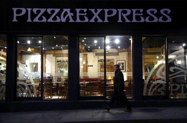 A person is seen walking past an empty Pizza Express restaurant in London on March 17, 2020. (Hannah McKay/Reuters)