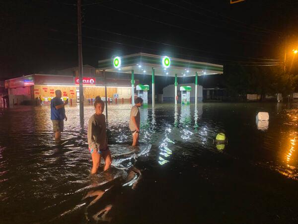 People walk on the flooded Sea Mountain Highway in North Myrtle Beach, S.C., as Isaias neared the Carolinas, Aug. 3, 2020. (Jason Lee/The Sun News via AP)